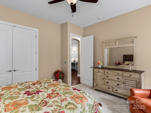 bedroom featuring a closet, arched walkways, light colored carpet, and ceiling fan