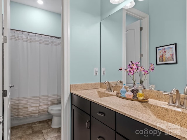 full bathroom featuring double vanity, shower / bath combination with curtain, toilet, and a sink