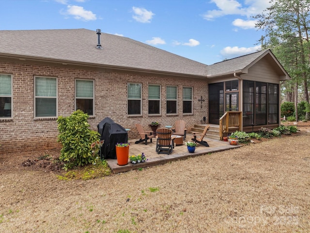 back of property with a patio, brick siding, a sunroom, and roof with shingles