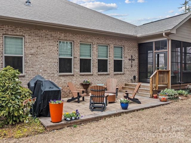 back of property with a patio, brick siding, roof with shingles, and a sunroom