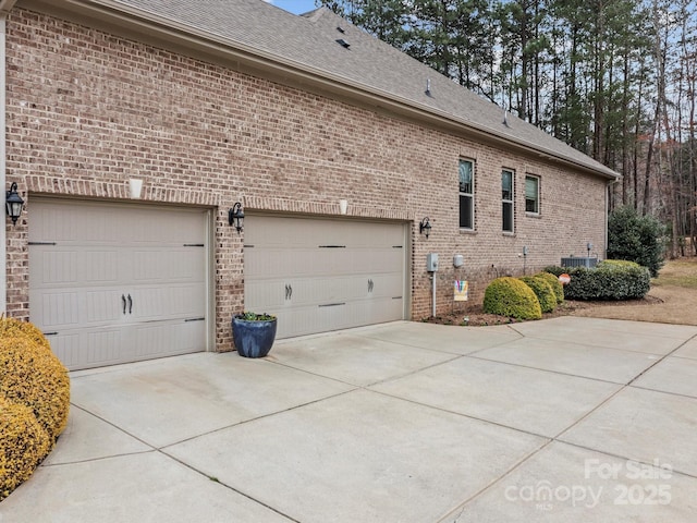 view of property exterior featuring brick siding, concrete driveway, a garage, and roof with shingles