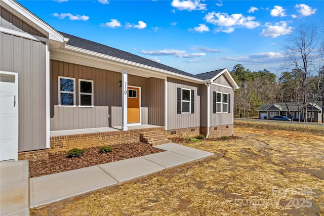 view of front facade featuring crawl space, covered porch, board and batten siding, and a shingled roof