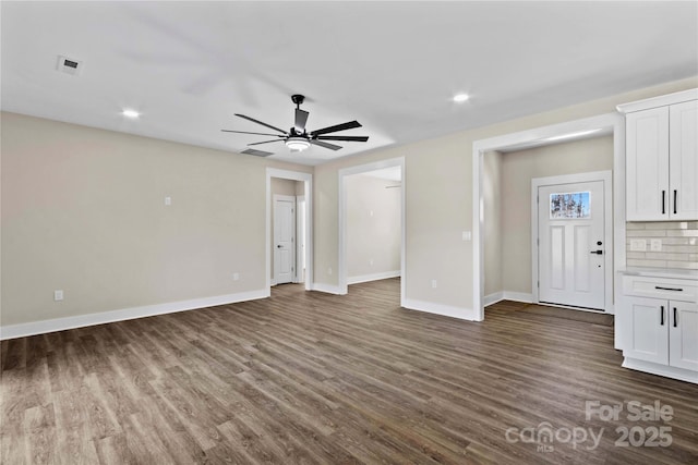 unfurnished living room featuring visible vents, baseboards, dark wood-type flooring, and ceiling fan