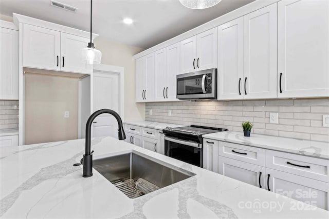 kitchen with a sink, stainless steel appliances, visible vents, and white cabinetry