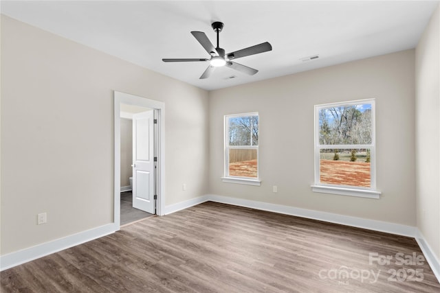 unfurnished bedroom with visible vents, multiple windows, baseboards, and dark wood-style flooring