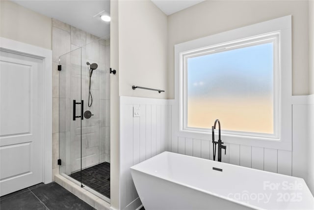 full bath with tile patterned floors, a wainscoted wall, a soaking tub, and a stall shower