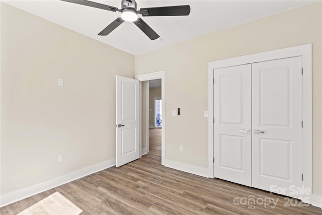 unfurnished bedroom featuring a closet, baseboards, wood finished floors, and a ceiling fan