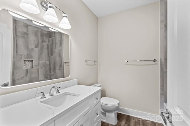 bathroom featuring toilet, wood finished floors, baseboards, walk in shower, and vanity