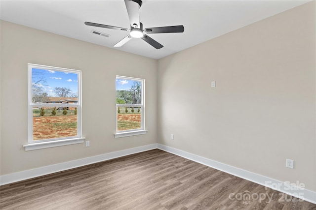 empty room with visible vents, ceiling fan, baseboards, and wood finished floors