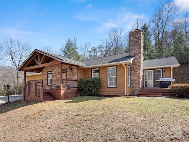 view of front of property with a front yard, roof with shingles, and a chimney