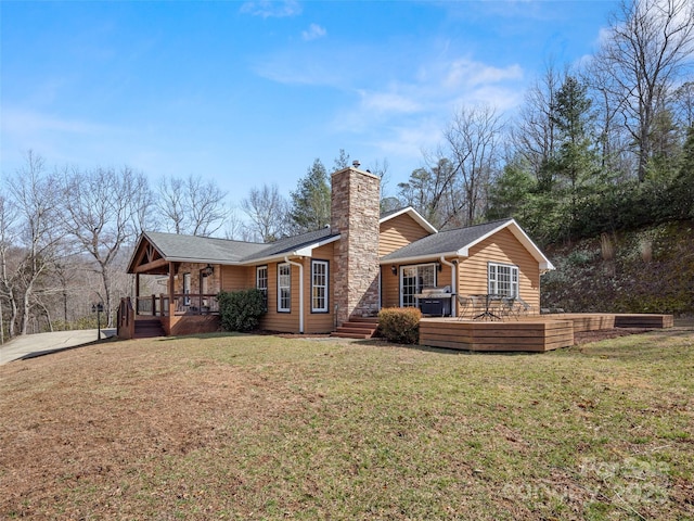 exterior space featuring a yard, a porch, a chimney, and a shingled roof