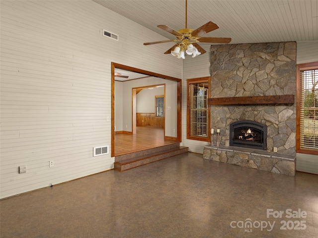 609 N Fork Rd, Black Mountain, NC 28711 - unfurnished living room with wood walls, ceiling fan, a stone fireplace, and finished concrete floors