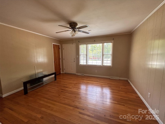 unfurnished living room featuring visible vents, wood finished floors, and ornamental molding