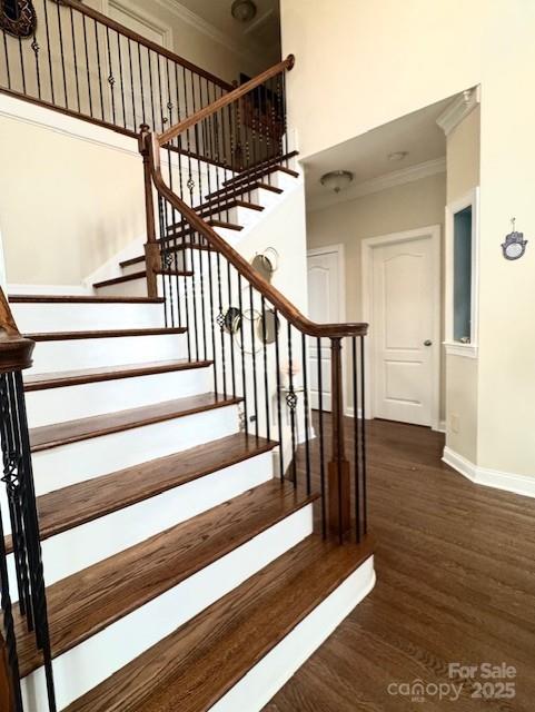 stairway with ornamental molding, baseboards, and wood finished floors