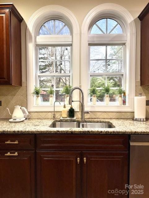 interior space with stainless steel dishwasher, decorative backsplash, and a sink