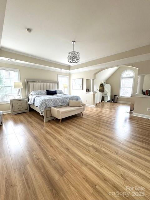 bedroom featuring light wood-type flooring, baseboards, and a raised ceiling