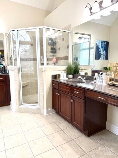 full bathroom featuring lofted ceiling, vanity, a shower stall, and tile patterned flooring