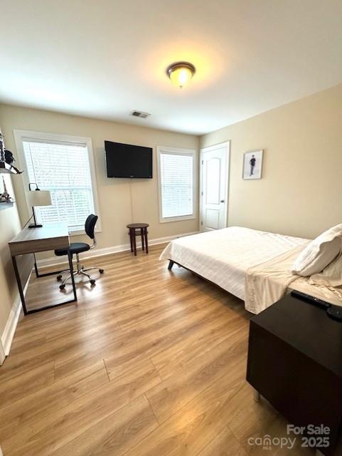 bedroom with light wood finished floors, visible vents, and baseboards