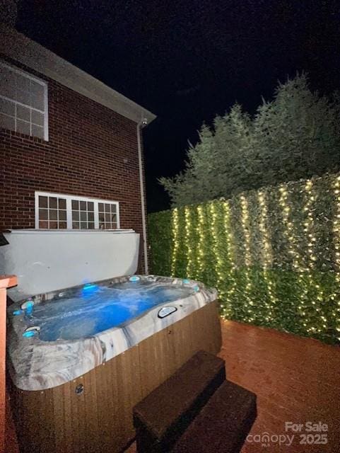 patio at twilight featuring a hot tub