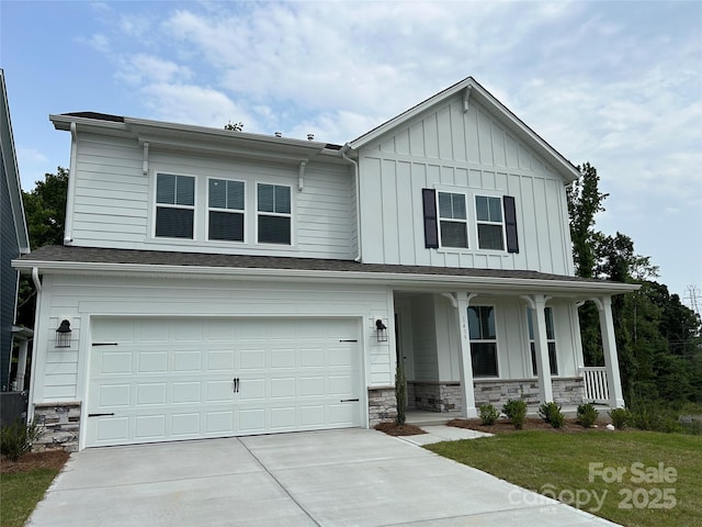 1439 Hubert Graham Way, Tega Cay, SC 29708 - view of front of home featuring board and batten siding, covered porch, an attached garage, driveway, and stone siding