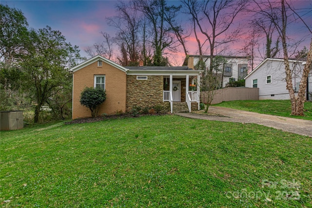 view of front facade featuring concrete driveway, a yard, brick siding, and covered porch