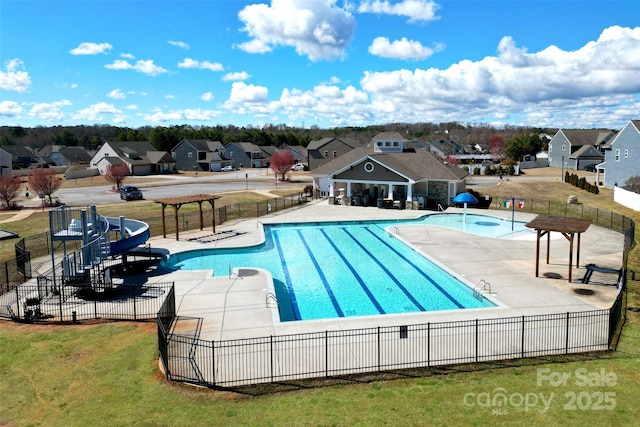 pool with a patio area, a residential view, a water slide, and fence
