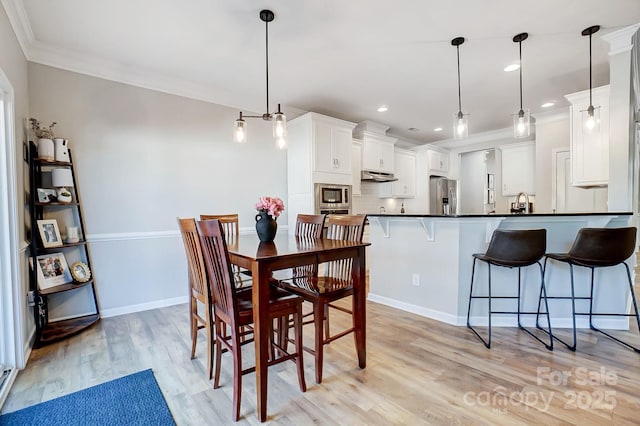dining area featuring recessed lighting, ornamental molding, light wood-style flooring, and baseboards