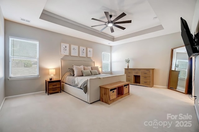 bedroom featuring carpet floors, visible vents, multiple windows, and a raised ceiling