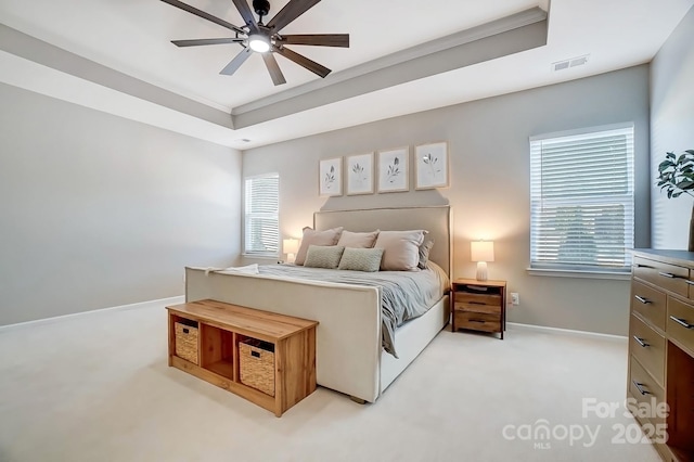 carpeted bedroom with a ceiling fan, crown molding, visible vents, baseboards, and a raised ceiling