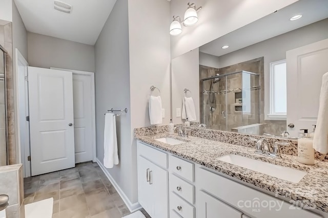 full bathroom featuring double vanity, baseboards, a shower stall, and a sink