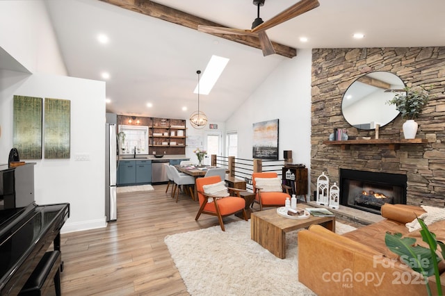 living room with high vaulted ceiling, beam ceiling, a skylight, a fireplace, and light wood-type flooring