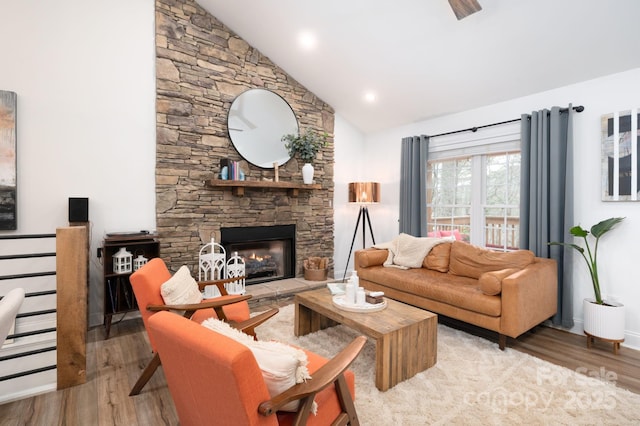 living area with a fireplace, high vaulted ceiling, baseboards, and wood finished floors