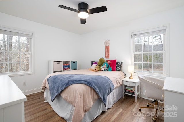 bedroom with baseboards, multiple windows, wood finished floors, and a ceiling fan