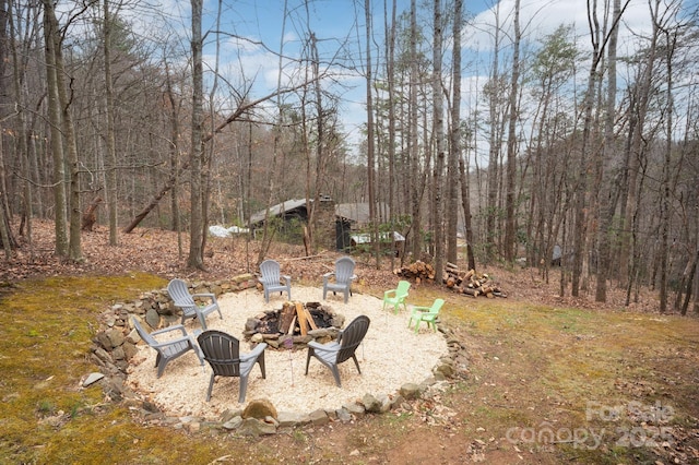 view of yard featuring a view of trees and a fire pit