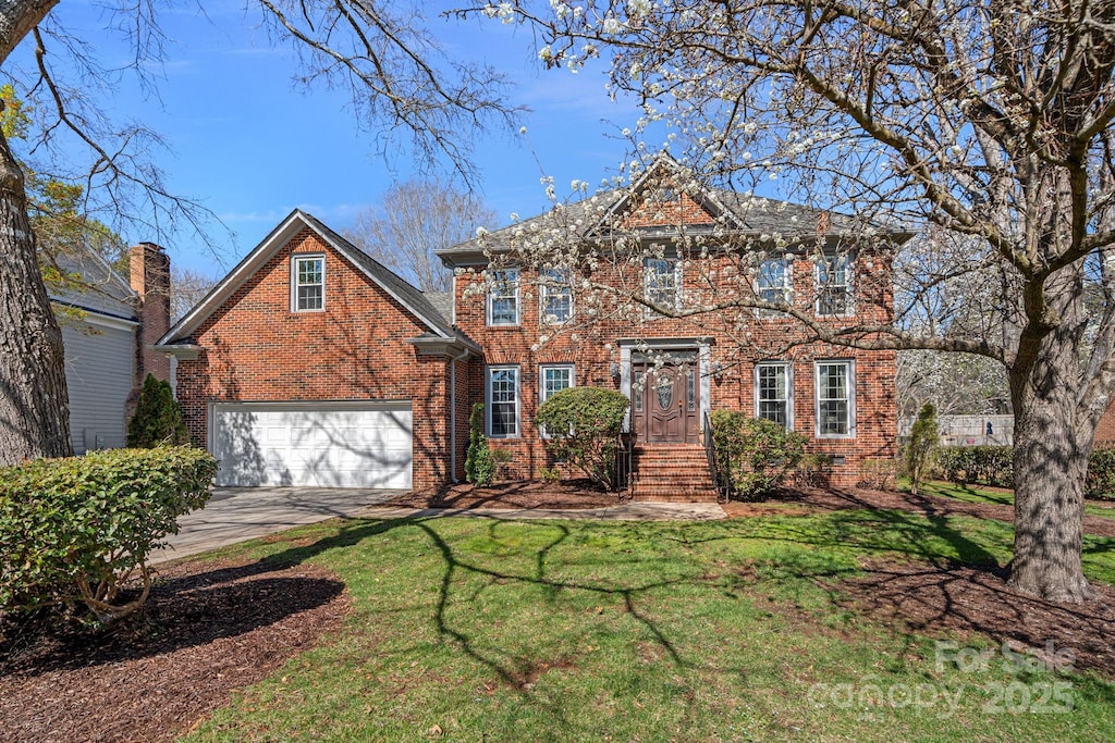 view of front of house with a front yard, brick siding, and driveway