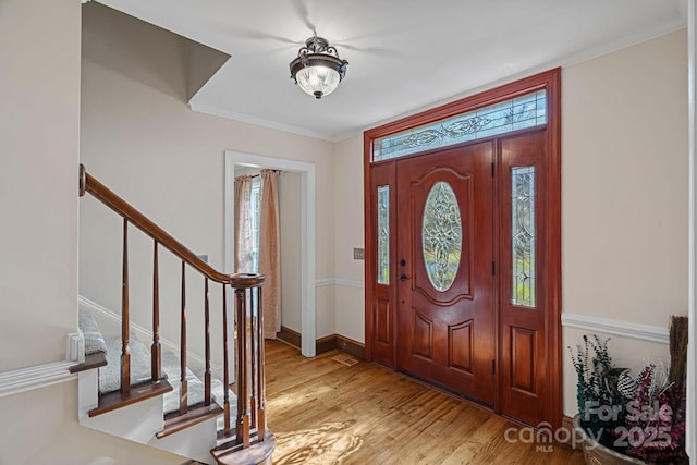 foyer with stairs, crown molding, wood finished floors, and baseboards