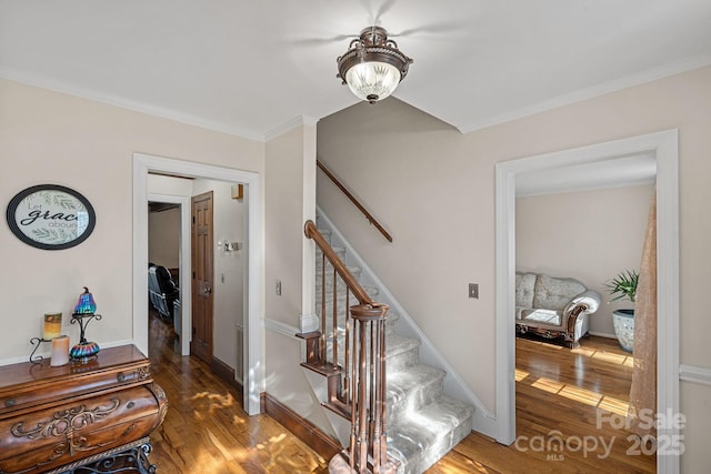 stairs featuring wood finished floors, baseboards, and ornamental molding