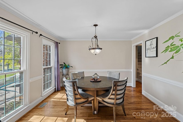 dining space featuring visible vents, baseboards, light wood-style floors, and crown molding