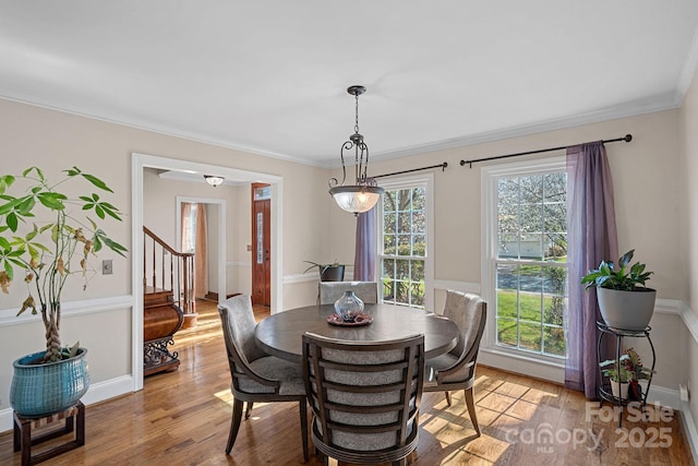 dining space with plenty of natural light, ornamental molding, and light wood finished floors