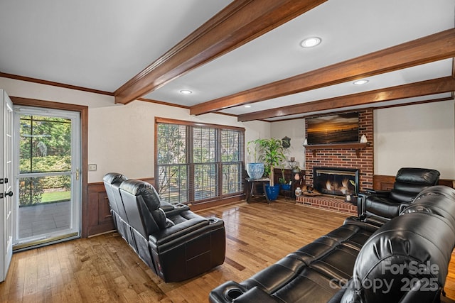 living room with a wainscoted wall, beamed ceiling, a fireplace, and wood-type flooring