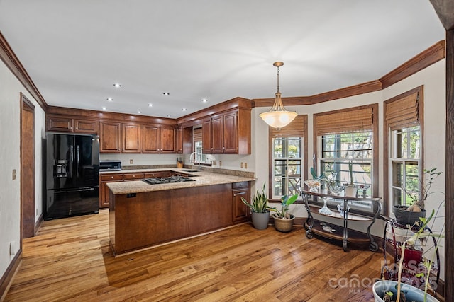 kitchen with black fridge, a peninsula, gas cooktop, and light wood-style floors