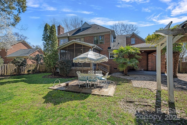 rear view of house with a lawn, a patio, fence, a sunroom, and a chimney