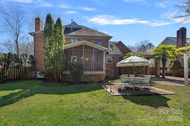 back of house with fence, a sunroom, a lawn, a patio area, and brick siding