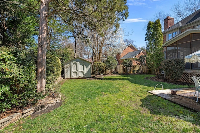 view of yard with an outbuilding, a shed, fence, and a sunroom