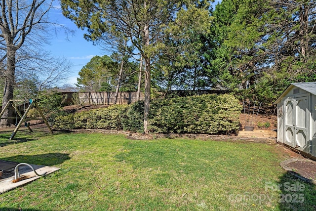 view of yard featuring a storage shed, a playground, an outbuilding, and fence