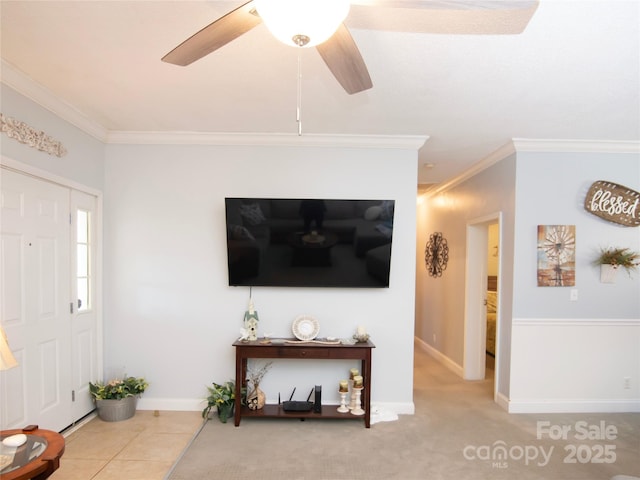 carpeted living area featuring tile patterned flooring, crown molding, baseboards, and ceiling fan