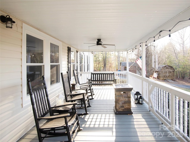 wooden terrace with an outbuilding, a shed, covered porch, and ceiling fan