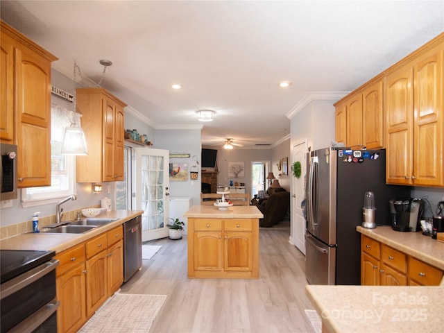 kitchen featuring open floor plan, light countertops, ornamental molding, appliances with stainless steel finishes, and a sink