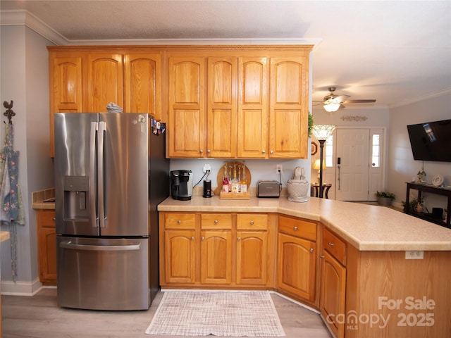 kitchen featuring stainless steel refrigerator with ice dispenser, a peninsula, crown molding, light countertops, and ceiling fan