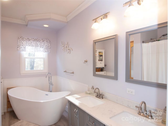 bathroom featuring a freestanding tub, ornamental molding, and a sink